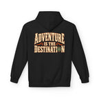 A black pullover hoodie shown from the back, featuring a large graphic print that reads 'ADVENTURE IS THE DESTINATION' in a distressed cream and orange font with a small compass design.