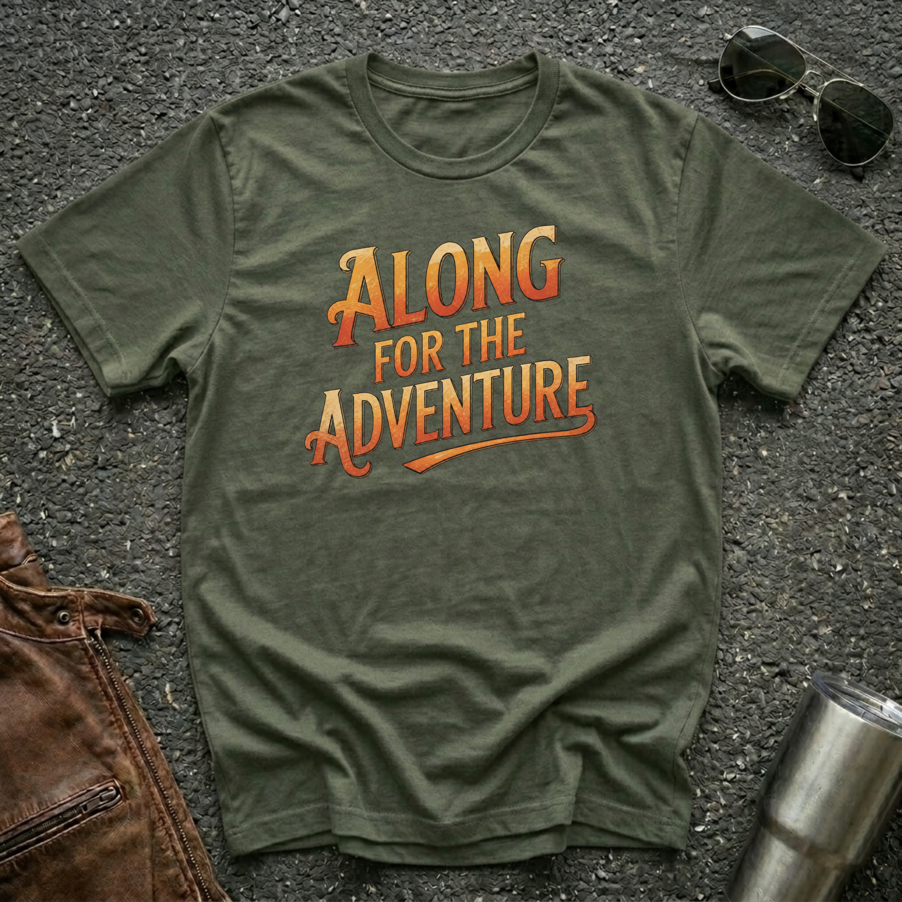 Military green 'Along For The Adventure' road trip t-shirt featuring vintage orange and gold typography on a soft unisex tee.
