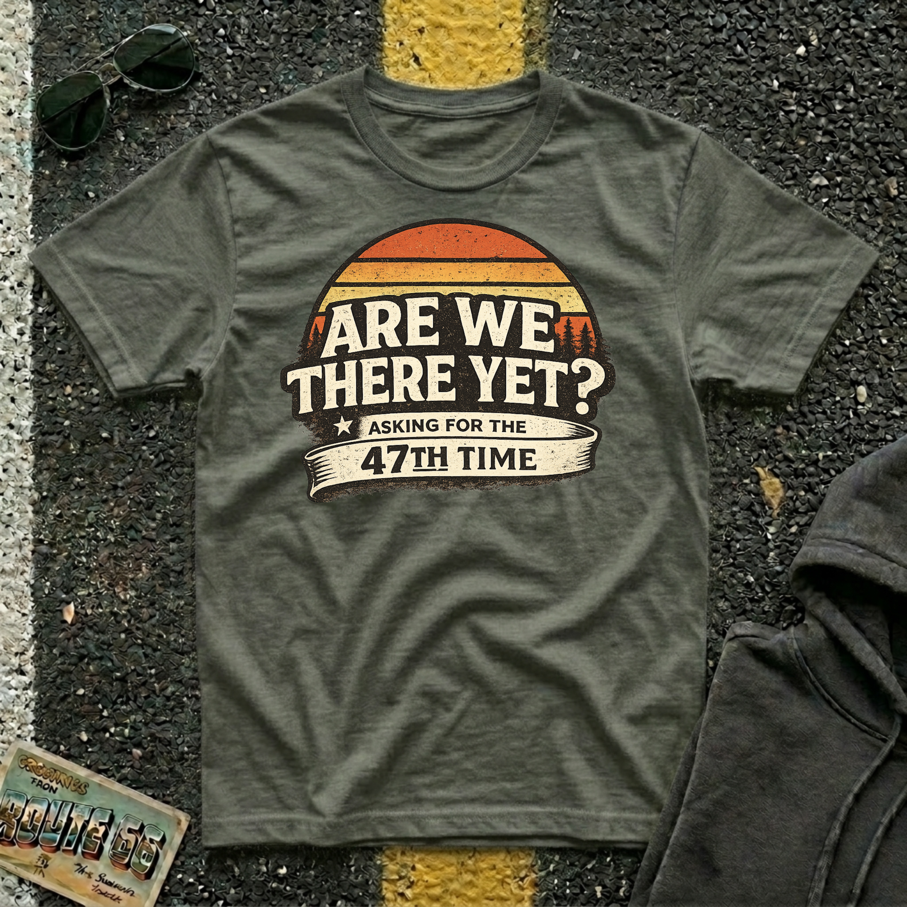 Are We There Yet? Asking for the 47th Time T-shirt by The Riverstone Life on a military green Gildan Softstyle 64000 featuring a humorous road trip design.