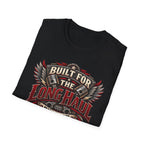 A black crewneck t-shirt folded neatly, featuring a large graphic print on the front with the words 'BUILT FOR THE LONG HAUL' in red and beige, flanked by metallic pistons and red wings, set against a plain white background.