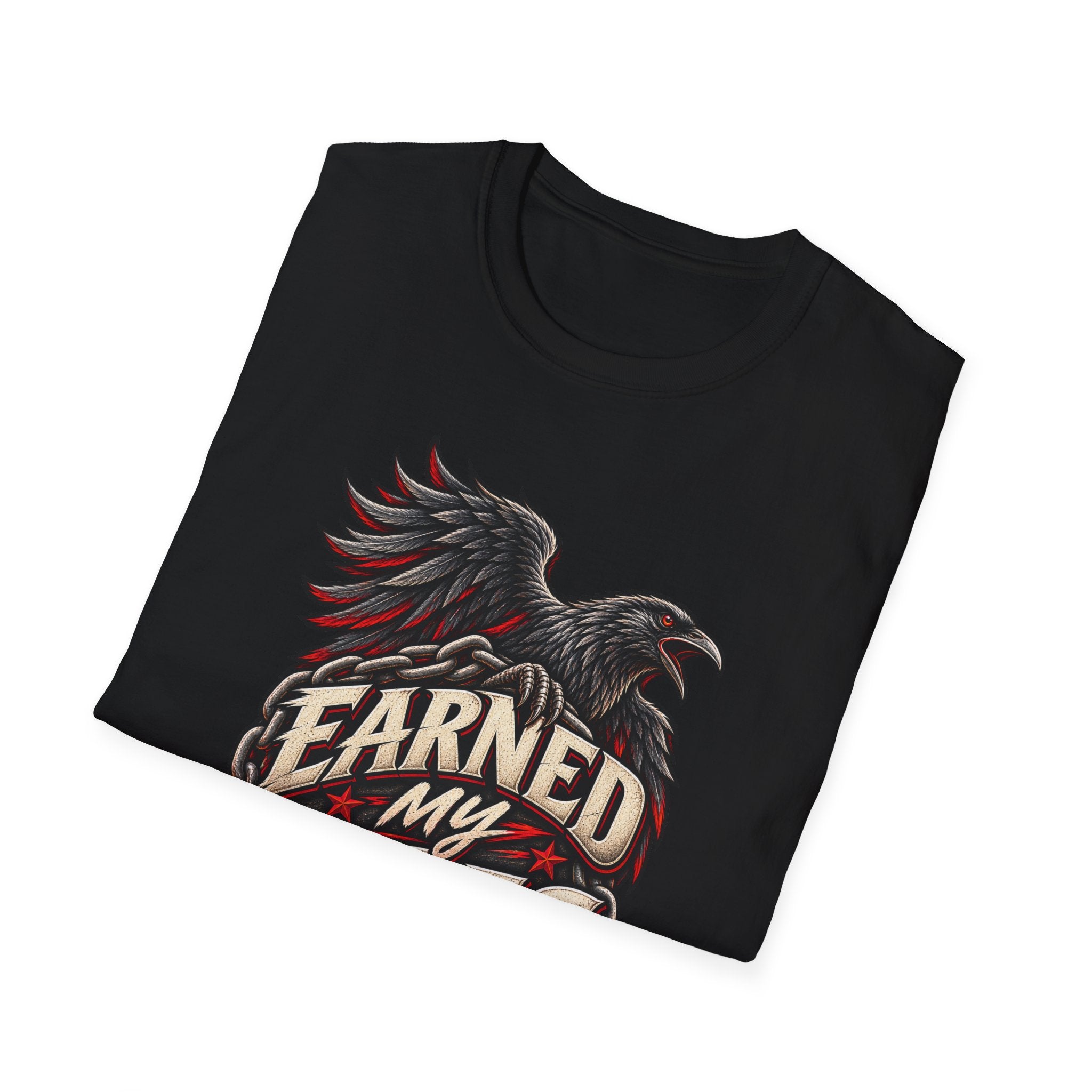 A folded black t-shirt with a graphic print of a raven and the text 'EARNED MY' in a distressed beige font with red accents, shown on a plain white background.