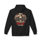 A black pullover hoodie shown from the back, featuring a large graphic print of a skull with wings and the text 'NOT DONE YET', 'STILL GOT', 'MILES TO RUN' in cream, red, and black.