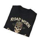 A folded black t-shirt with a graphic print of a skull wearing a cowboy hat and the text 'ROAD WORN STILL ROLLING' in a distressed beige font, shown on a plain white background.