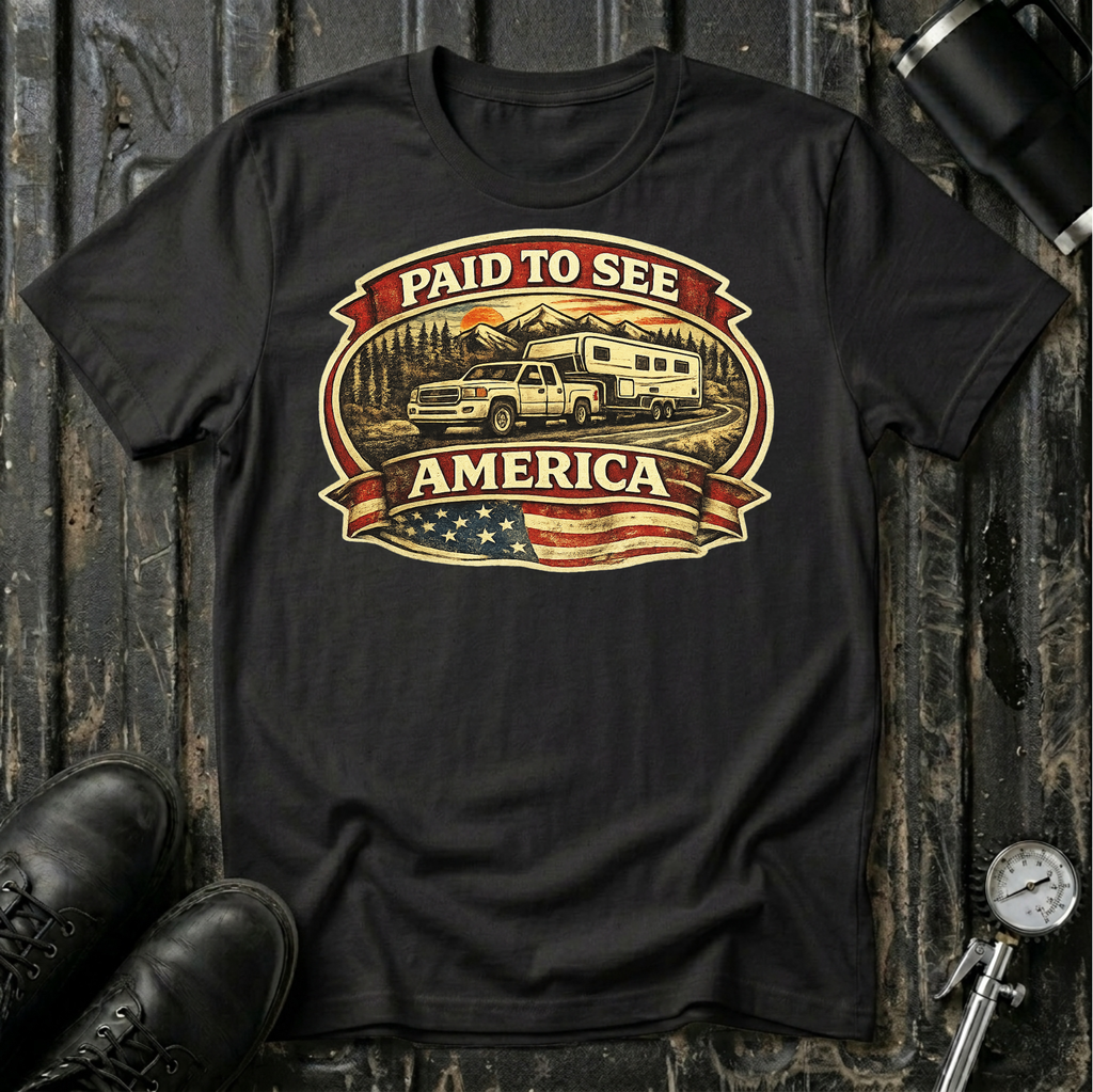 Paid to See America light truck T-shirt by The Riverstone Life on a black Gildan Softstyle 64000 featuring a pickup truck hauling a fifth-wheel with an American flag and scenic landscape.
