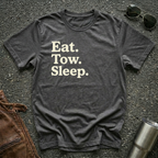 A dark heather crewneck t-shirt with the text 'Eat. Tow. Sleep.' flat lay.