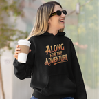 A woman wearing a black hoodie with the text 'ALONG FOR THE ADVENTURE' in a stylized orange and brown font, holding a white coffee cup outdoors.