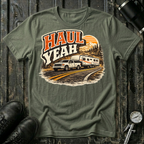 Haul Yeah RV Transport T-shirt by The Riverstone Life on a military green Gildan Softstyle 64000 featuring a pickup truck towing a fifth-wheel RV.