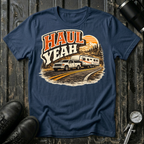 Haul Yeah RV Transport T-shirt by The Riverstone Life on a navy blue Gildan Softstyle 64000 featuring a pickup truck towing a fifth-wheel RV.