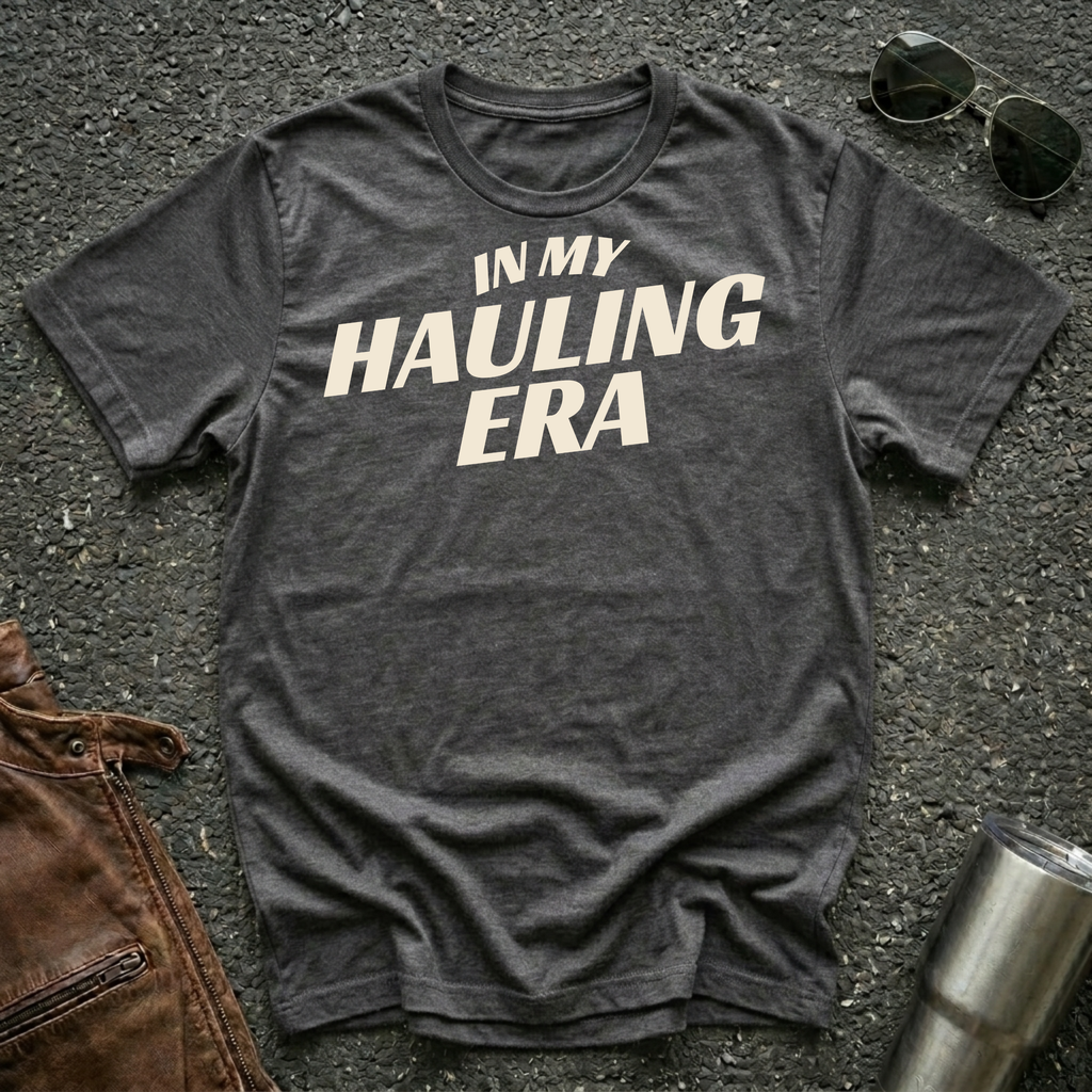 Dark heather 'In My Hauling Era' road life t-shirt featuring bold cream typography on a soft unisex tee.