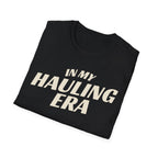 Folded black 'In My Hauling Era' road life t-shirt featuring bold cream typography on a soft unisex tee.