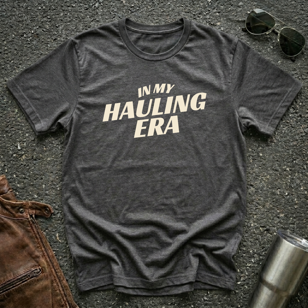 Dark heather 'In My Hauling Era' road life t-shirt featuring bold cream typography on a soft unisex tee.