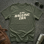 Military green 'In My Hauling Era' road life t-shirt featuring bold cream typography on a soft unisex tee.