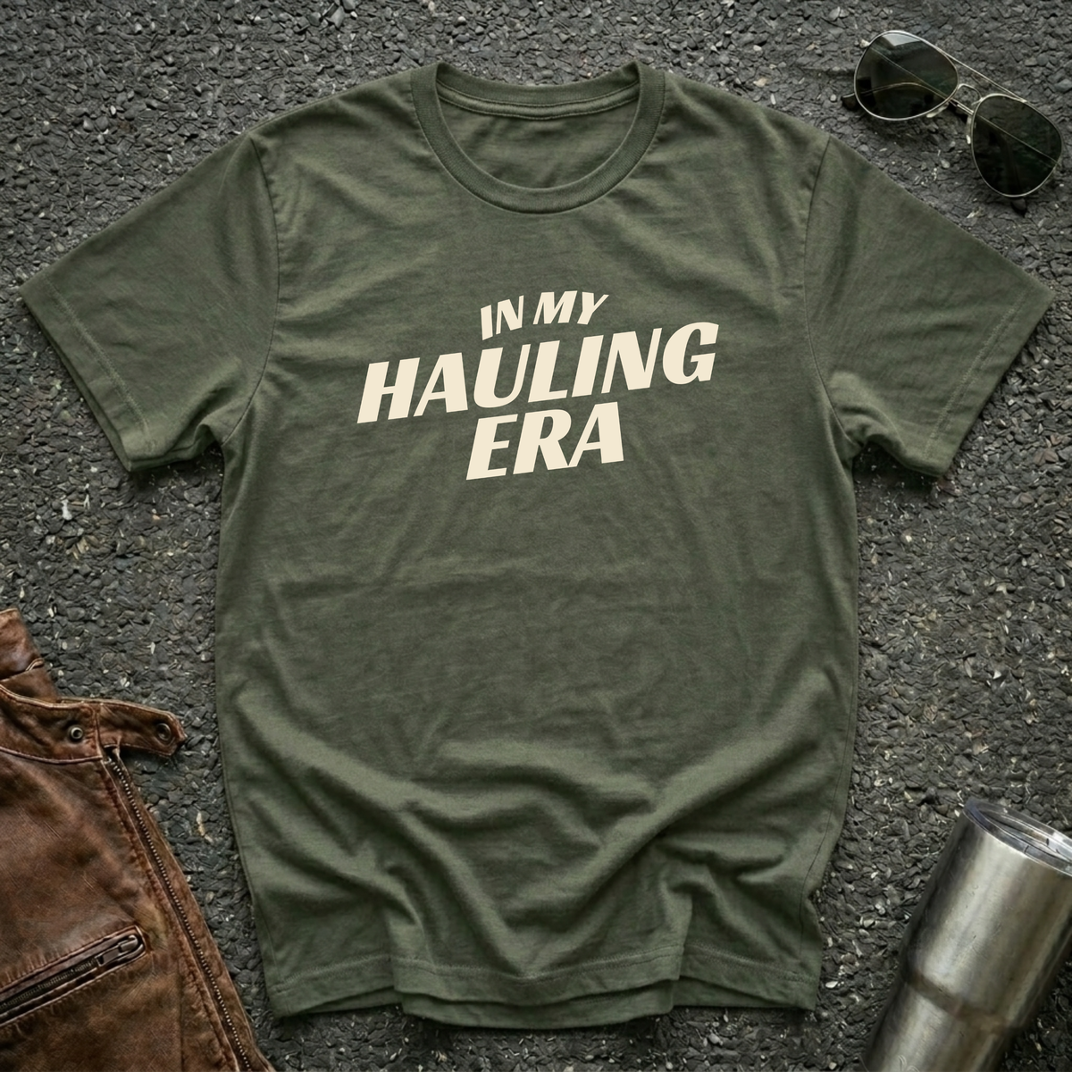 Military green 'In My Hauling Era' road life t-shirt featuring bold cream typography on a soft unisex tee.