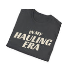 Folded dark heather 'In My Hauling Era' road life t-shirt featuring bold cream typography on a soft unisex tee.