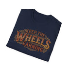 Navy folded 'Keep The Wheels Earning' vintage RV Transport T-shirt featuring vintage gold and rust typography on a soft unisex tee on a white background.