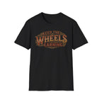Black 'Keep The Wheels Earning' vintage RV Transport T-shirt featuring vintage gold and rust typography on a soft unisex tee on a white background.