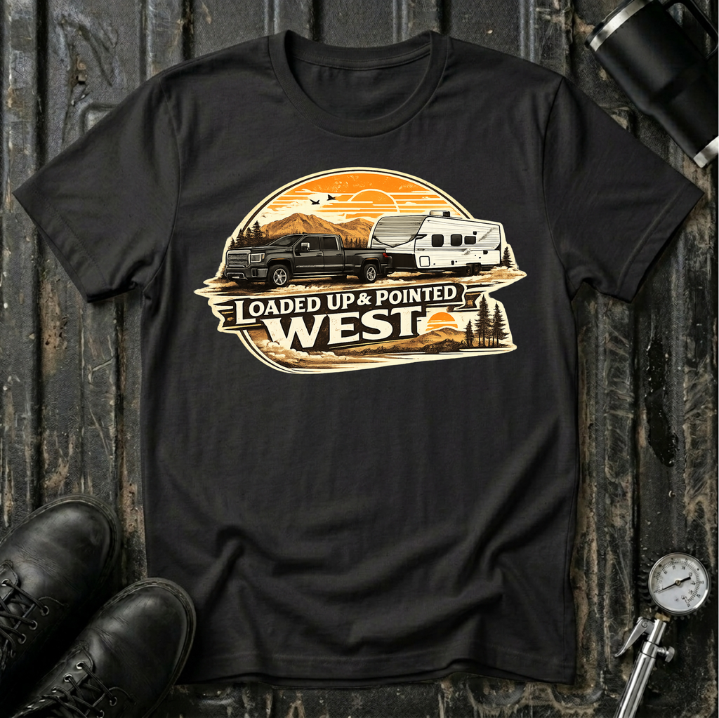 Loaded Up & Pointed West T-shirt by The Riverstone Life on a black Gildan Softstyle 64000 featuring a pickup truck towing a camper RV toward a western sunset.