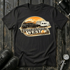 Loaded Up & Pointed West T-shirt by The Riverstone Life on a black Gildan Softstyle 64000 featuring a pickup truck towing a camper RV toward a western sunset.