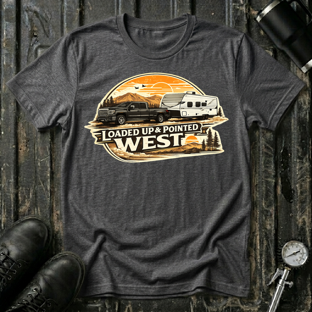 Loaded Up & Pointed West T-shirt by The Riverstone Life on a dark heather Gildan Softstyle 64000 featuring a pickup truck towing a camper toward a western sunset.