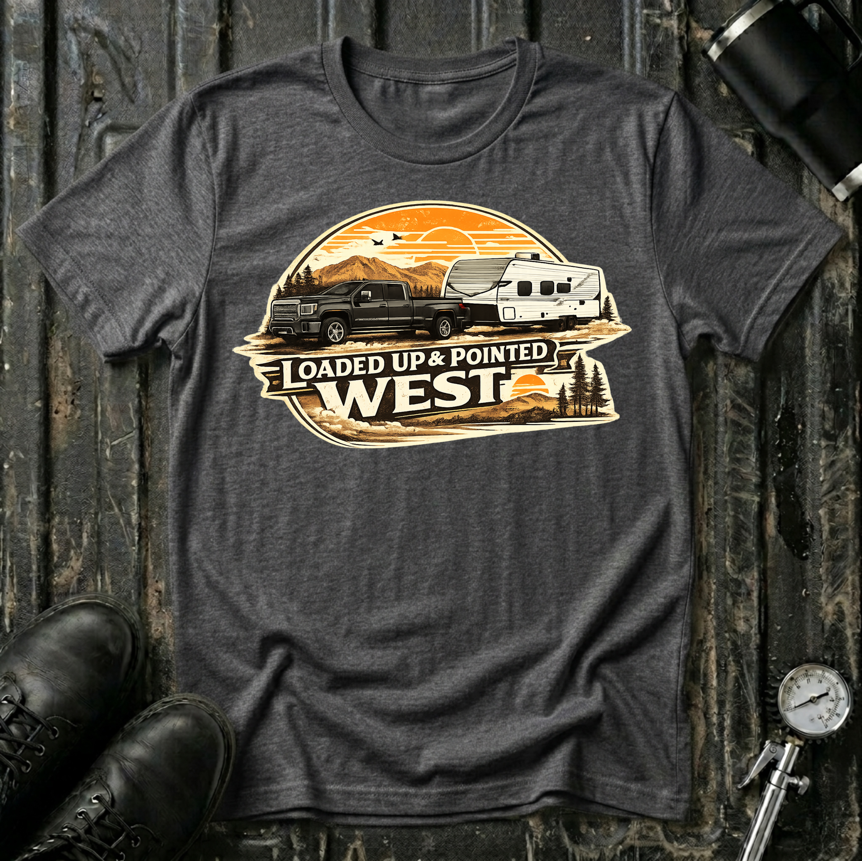 Loaded Up & Pointed West T-shirt by The Riverstone Life on a dark heather Gildan Softstyle 64000 featuring a pickup truck towing a camper toward a western sunset.