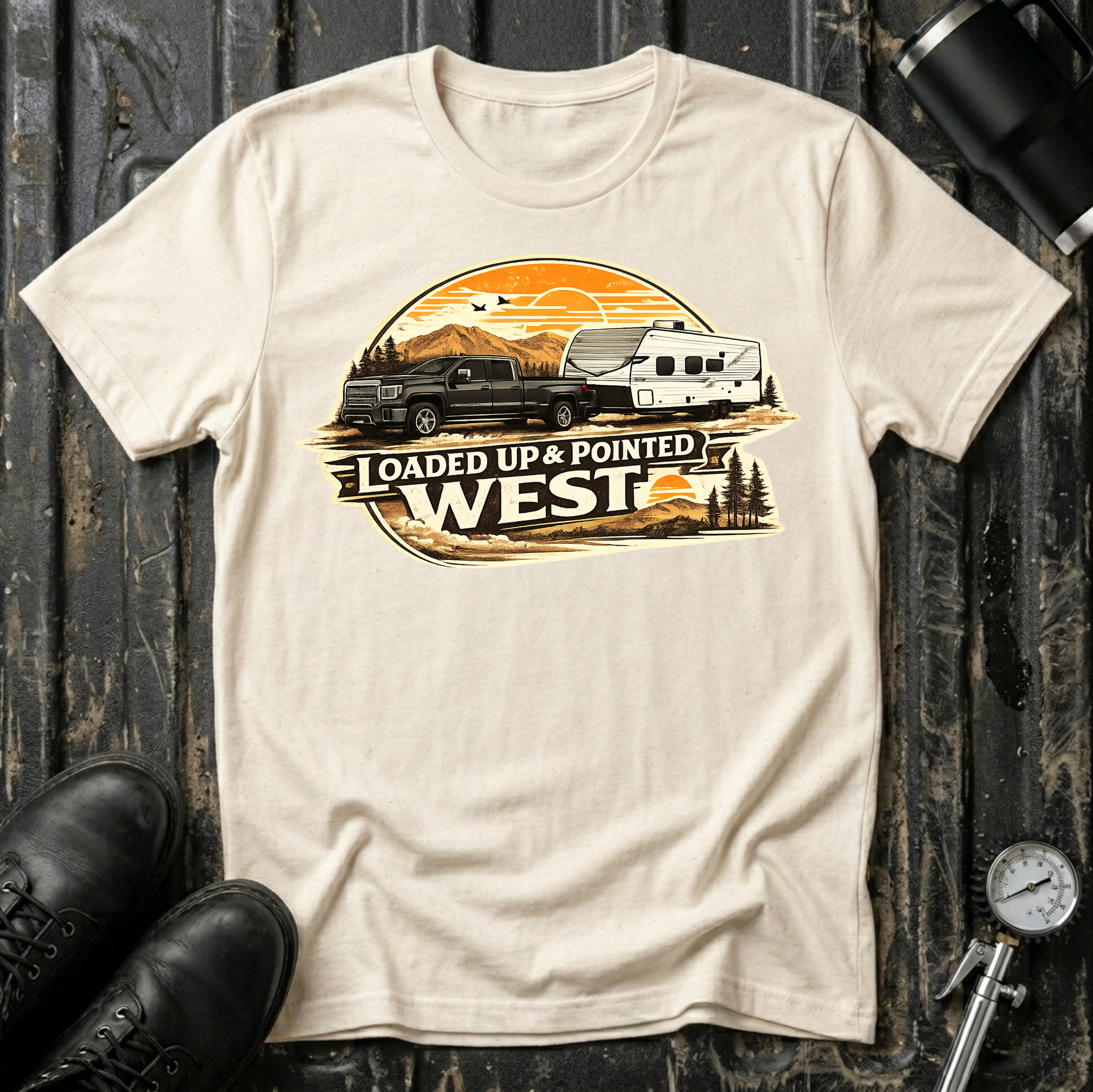 Loaded Up & Pointed West T-shirt by The Riverstone Life on a natural Gildan Softstyle 64000 featuring a pickup truck towing a camper toward a western sunset.