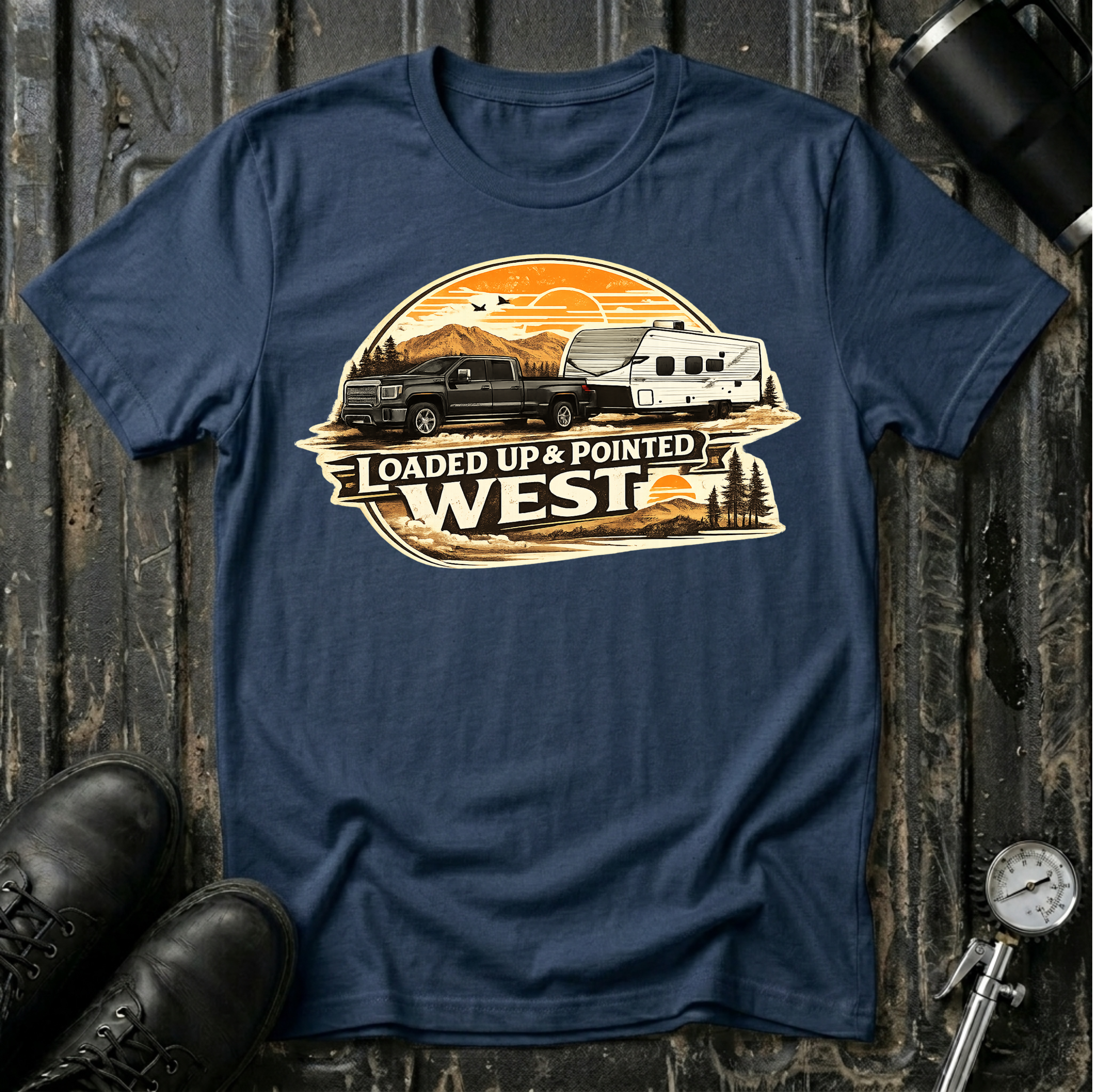 Loaded Up & Pointed West T-shirt by The Riverstone Life on a navy Gildan Softstyle 64000 featuring a pickup truck towing a camper RV toward a western sunset.