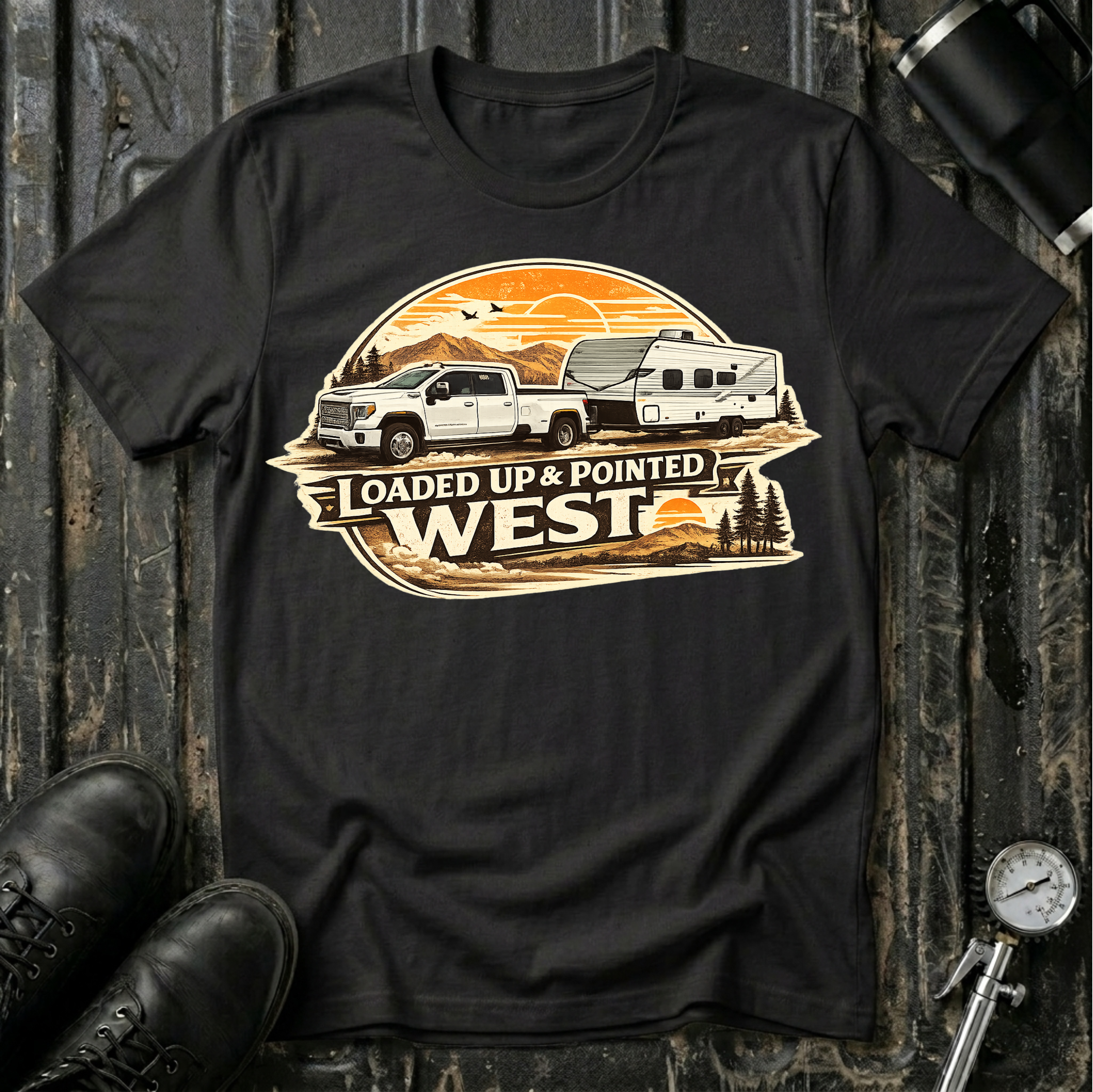Loaded Up & Pointed West T-shirt by The Riverstone Life on a black Gildan Softstyle 64000 featuring a pickup truck towing a camper toward a western sunset.