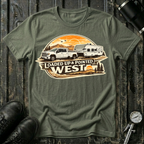 Loaded Up & Pointed West T-shirt by The Riverstone Life on a military green Gildan Softstyle 64000 featuring a pickup truck towing a camper toward a western sunset.
