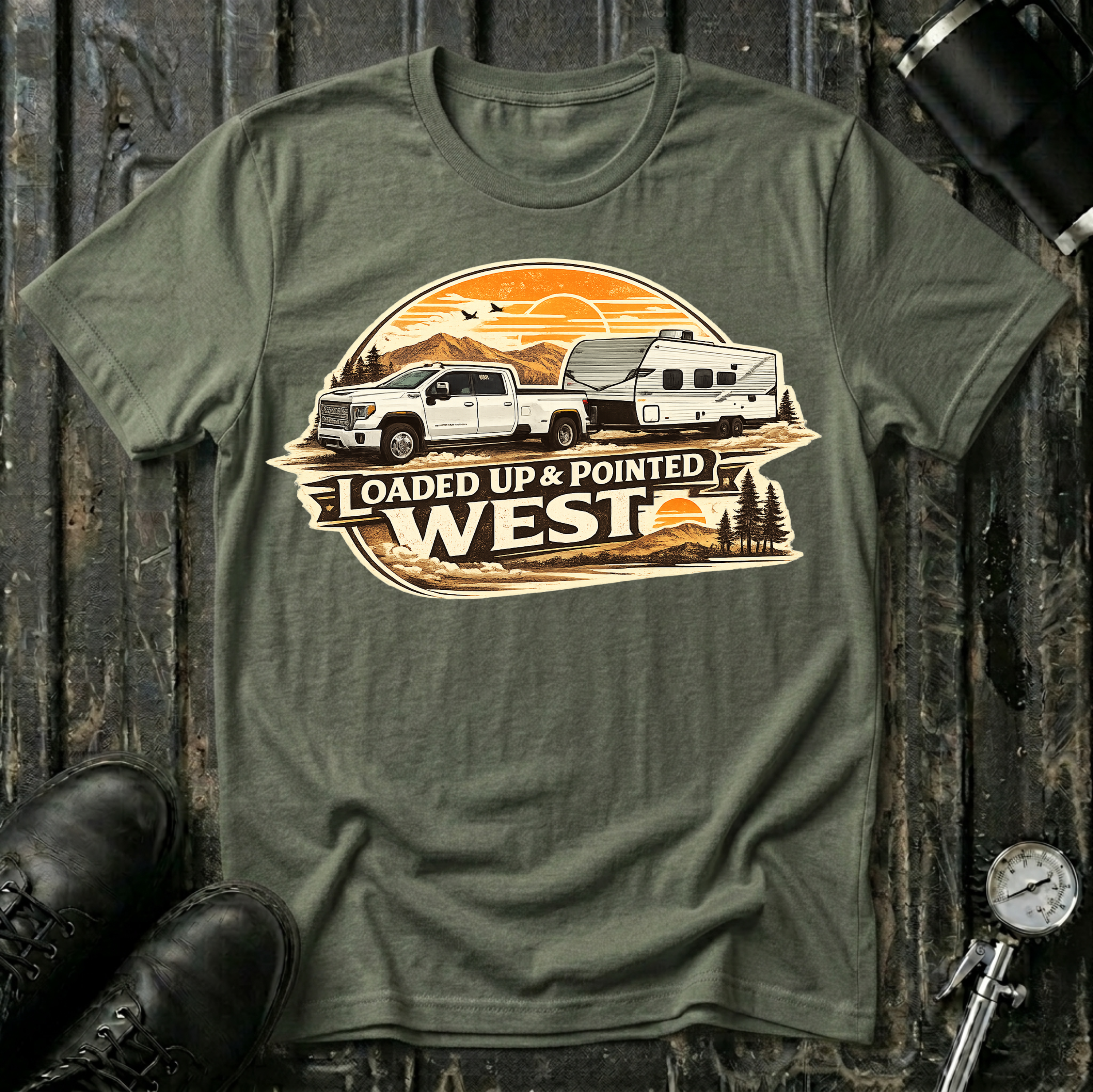 Loaded Up & Pointed West T-shirt by The Riverstone Life on a military green Gildan Softstyle 64000 featuring a pickup truck towing a camper toward a western sunset.