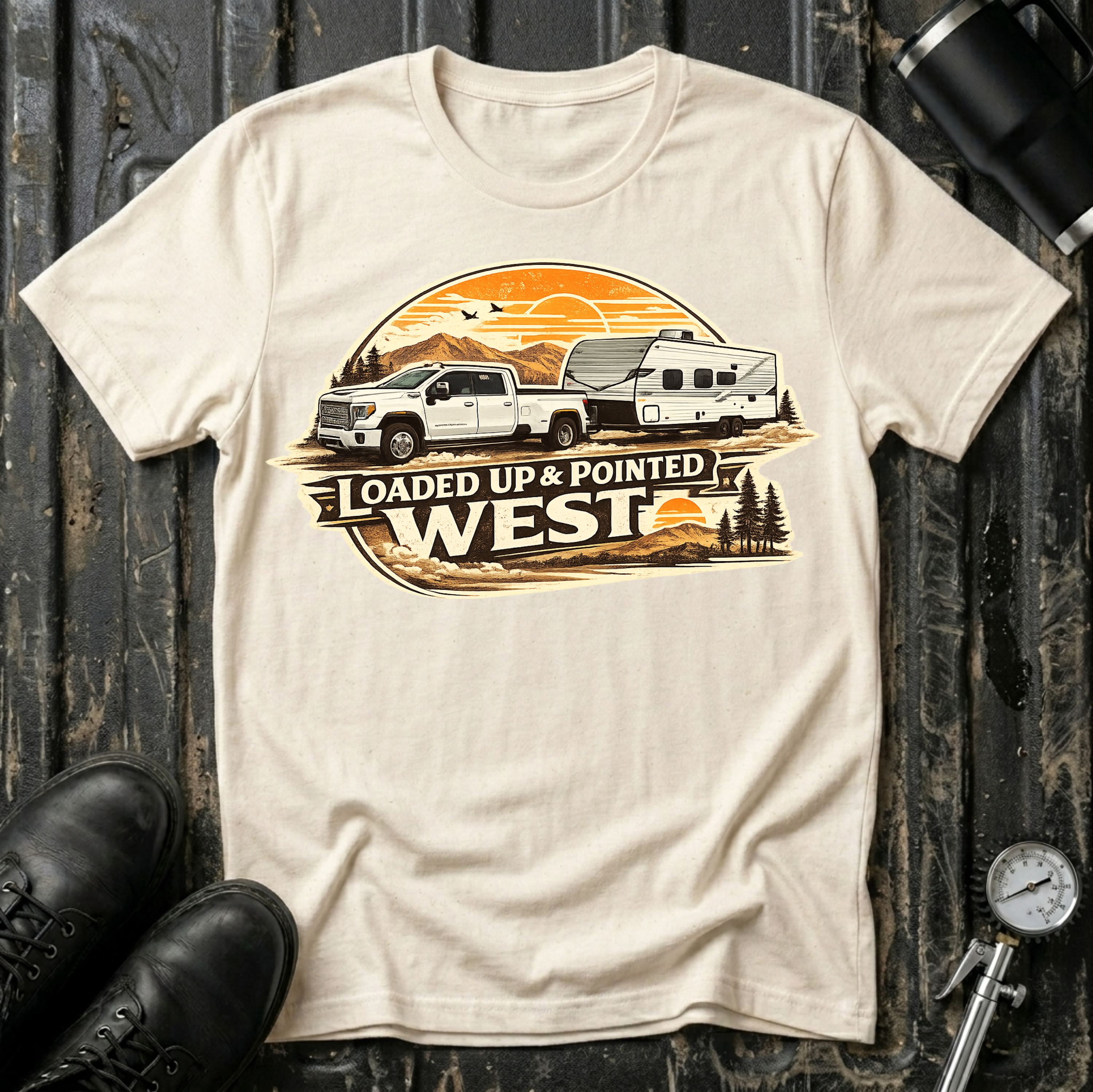 Loaded Up & Pointed West T-shirt by The Riverstone Life on a natural Gildan Softstyle 64000 featuring a pickup truck towing a camper toward a western sunset.