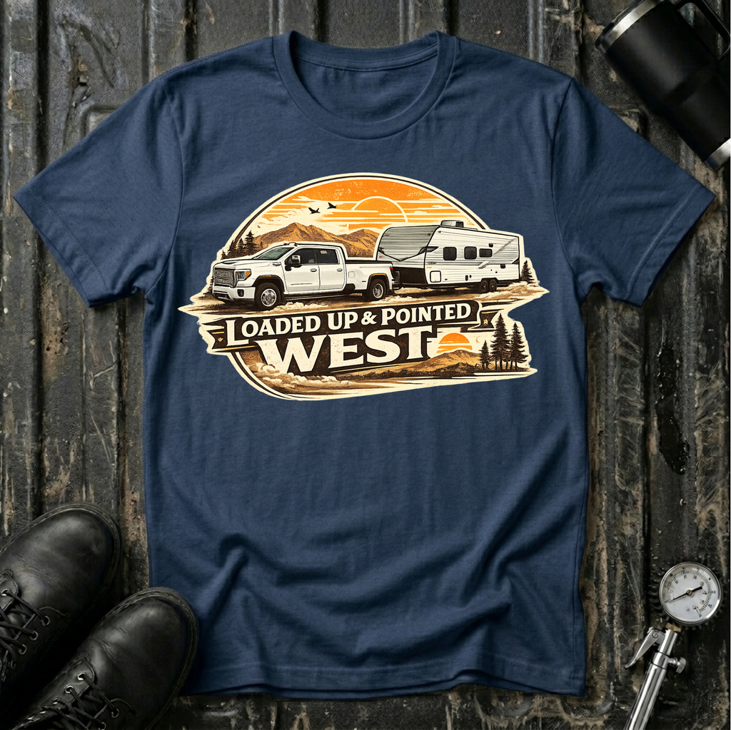 Loaded Up & Pointed West T-shirt by The Riverstone Life on a navy Gildan Softstyle 64000 featuring a pickup truck towing a camper toward a western sunset.