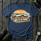 Loaded Up & Pointed West T-shirt by The Riverstone Life on a navy Gildan Softstyle 64000 featuring a pickup truck towing a camper toward a western sunset.