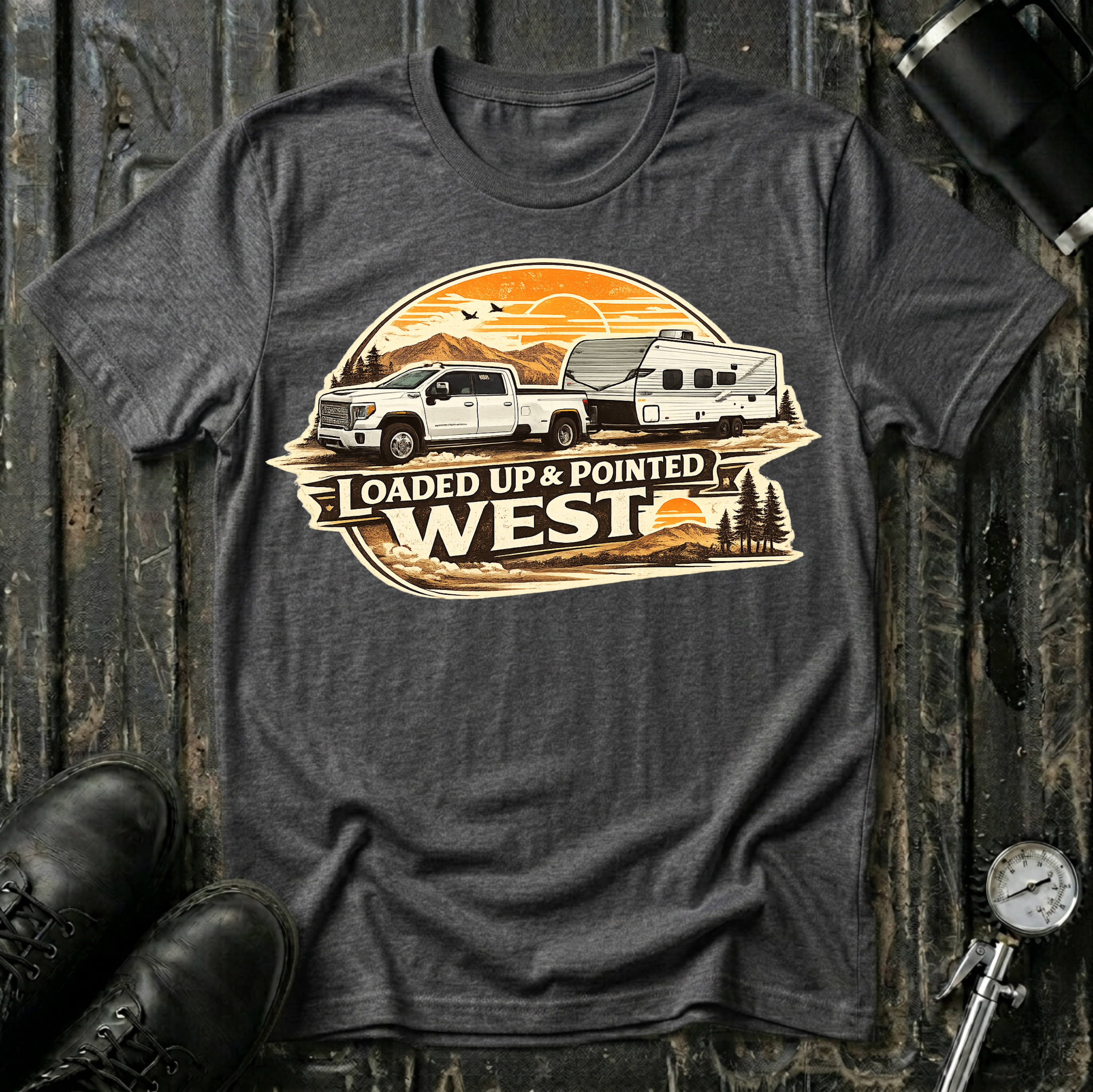 Loaded Up & Pointed West light truck T-shirt by The Riverstone Life on a dark heather Gildan Softstyle 64000 featuring a pickup truck towing a camper towards a western sunset.