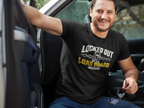 A smiling man sitting in a car wearing a black graphic t-shirt with the text 'LOCKED OUT OF THE LOAD BOARD AGAIN!' in white and yellow, along with a padlock and chain design.