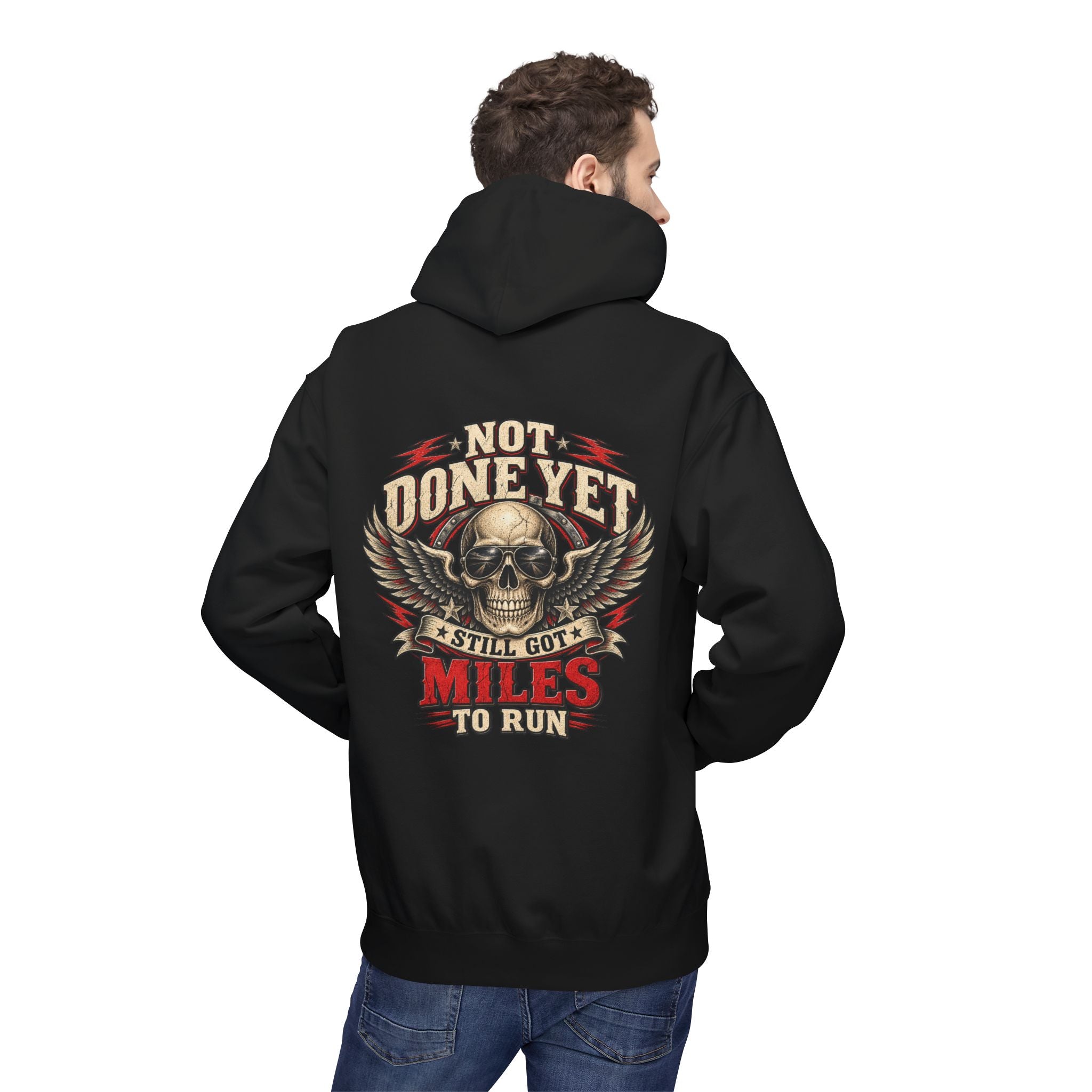 A man shown from the back wearing a black hoodie with a large graphic print on the back. The design features a skull with wings and the text 'NOT DONE YET', 'STILL GOT', 'MILES TO RUN' in red, beige, and white.