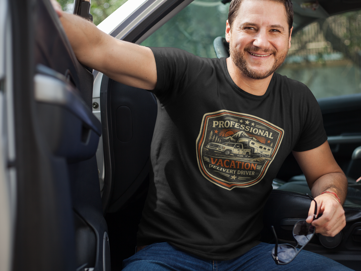 A smiling man sitting in a truck wearing a black graphic t-shirt with a vintage-style 'Professional Vacation Delivery Driver' shield logo on the chest.