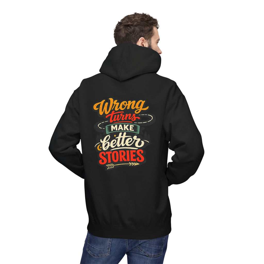 A man wearing a black hoodie, viewed from the back, featuring a colorful retro-style graphic on the back that reads 'Wrong Turns Make Better Stories' in orange, red, and cream lettering.