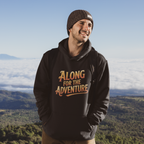 A man wearing a black hoodie with the text 'ALONG FOR THE ADVENTURE' in orange and yellow, standing outdoors with a mountain and cloud landscape in the background.