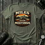 Miles Over Meeting T-shirt by The Riverstone Life on a military green Gildan Softstyle 64000 featuring a vintage highway and mountain design.