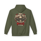 An military green pullover hoodie shown from the back, featuring a large graphic print of a skull with wings and the text 'NOT DONE YET', 'STILL GOT', 'MILES TO RUN' in cream, red, and black.