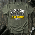 An military green graphic t-shirt laid flat on a dark rustic wooden background, styled with black leather boots and a bicycle pump. The t-shirt features a graphic print that reads 'LOCKED OUT OF THE LOAD BOARD AGAIN!' in white and yellow lettering with a padlock and chain illustration.