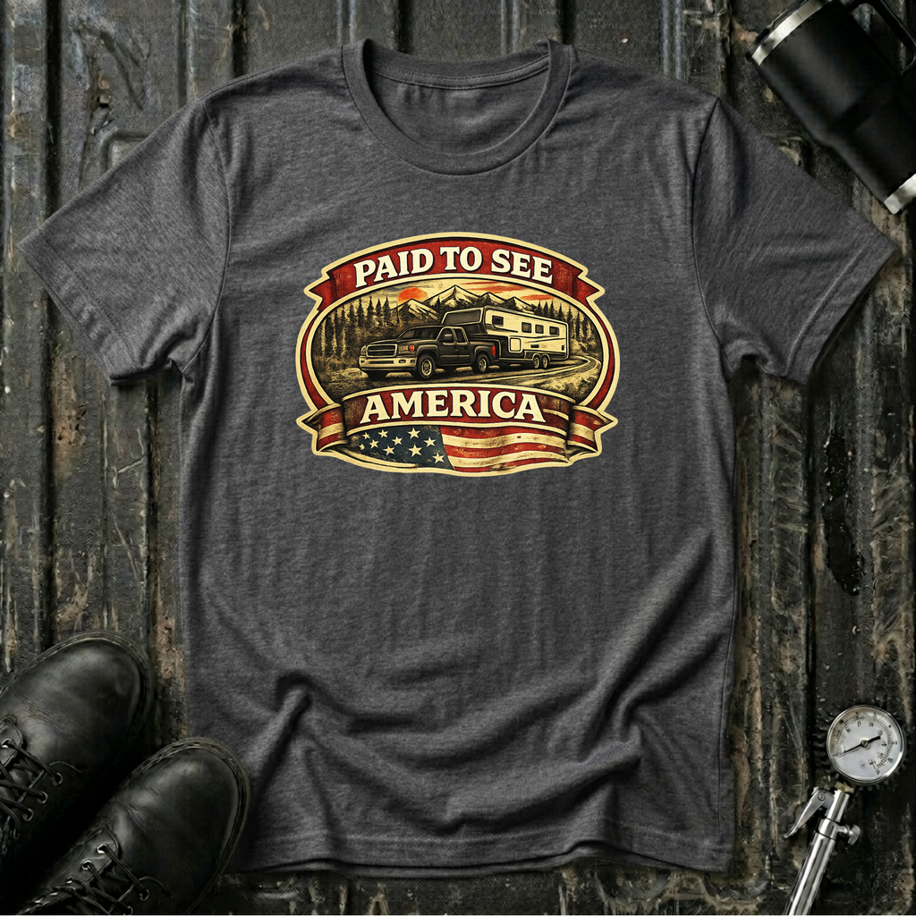 Dark heather RV Transport T-shirt featuring a dark pickup truck towing a camper, an American flag, and the phrase "Paid to See America"
