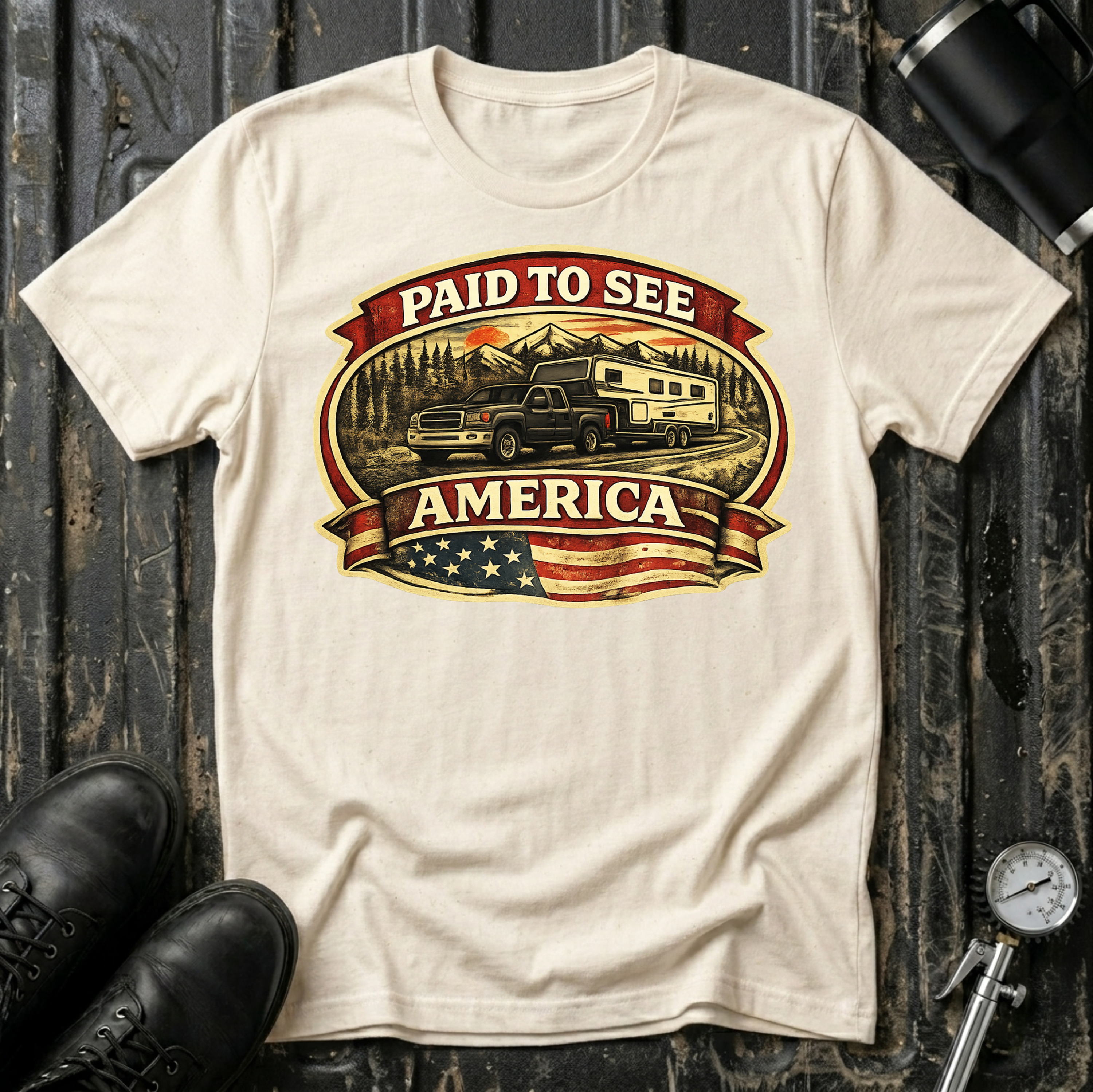 Paid to See America dark truck T-shirt by The Riverstone Life on a natural Gildan Softstyle 64000 featuring a pickup truck hauling a fifth-wheel with an American flag and scenic landscape.