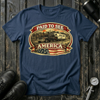 Paid to See America dark truck T-shirt by The Riverstone Life on a navy Gildan Softstyle 64000 featuring a pickup truck hauling a fifth-wheel with an American flag and scenic landscape.