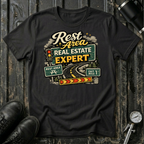Rest Area Real Estate Expert T-shirt by The Riverstone Life featuring a black Gildan Softstyle 64000 featuring a humorous highway and rest area design for RV Transport drivers and road travelers.