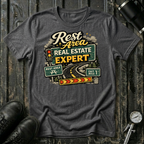Rest Area Real Estate Expert T-shirt by The Riverstone Life featuring a dark heather Gildan Softstyle 64000 featuring a humorous highway and rest area design for RV Transport drivers and road travelers.