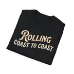 A folded black t-shirt with the phrase 'ROLLING COAST TO COAST' printed across the front in a cream-colored retro font with a maroon shadow outline, shown on a plain white background.