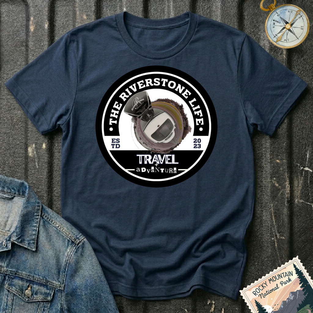 The Riverstone Life 2023 T-shirt by The Riverstone Life on a navy Gildan Softstyle 64000 featuring the official circular travel logo with a pickup truck and fifth-wheel RV.