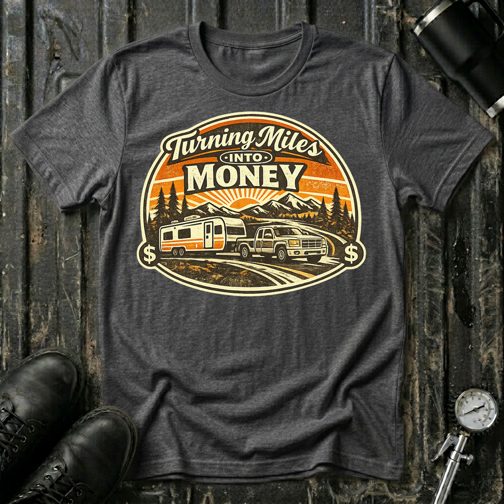 Turning Miles Into Money T-Shirt by The Riverstone Life on a dark heather Gildan Softstyle 64000 featuring a pickup truck hauling an RV through a mountain landscape.