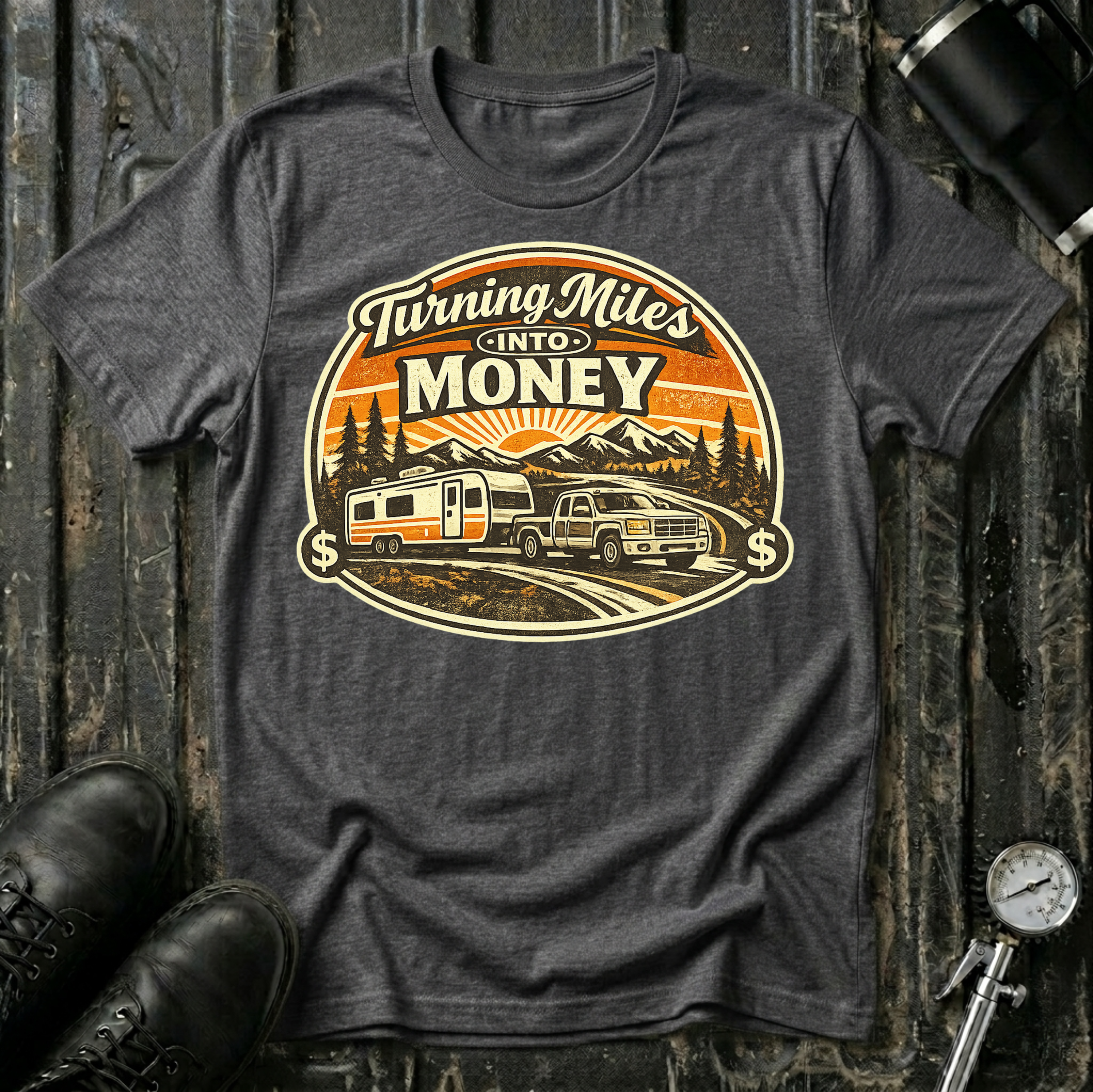 Turning Miles Into Money T-Shirt by The Riverstone Life on a dark heather Gildan Softstyle 64000 featuring a pickup truck hauling an RV through a mountain landscape.